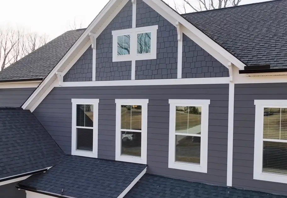 Modern gray gabled house exterior with white trim, dark shingle roofs, and multiple windows, conveying a clean, peaceful residential feel.